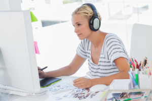 Cheerful photo editor working with graphics tablet at her desk